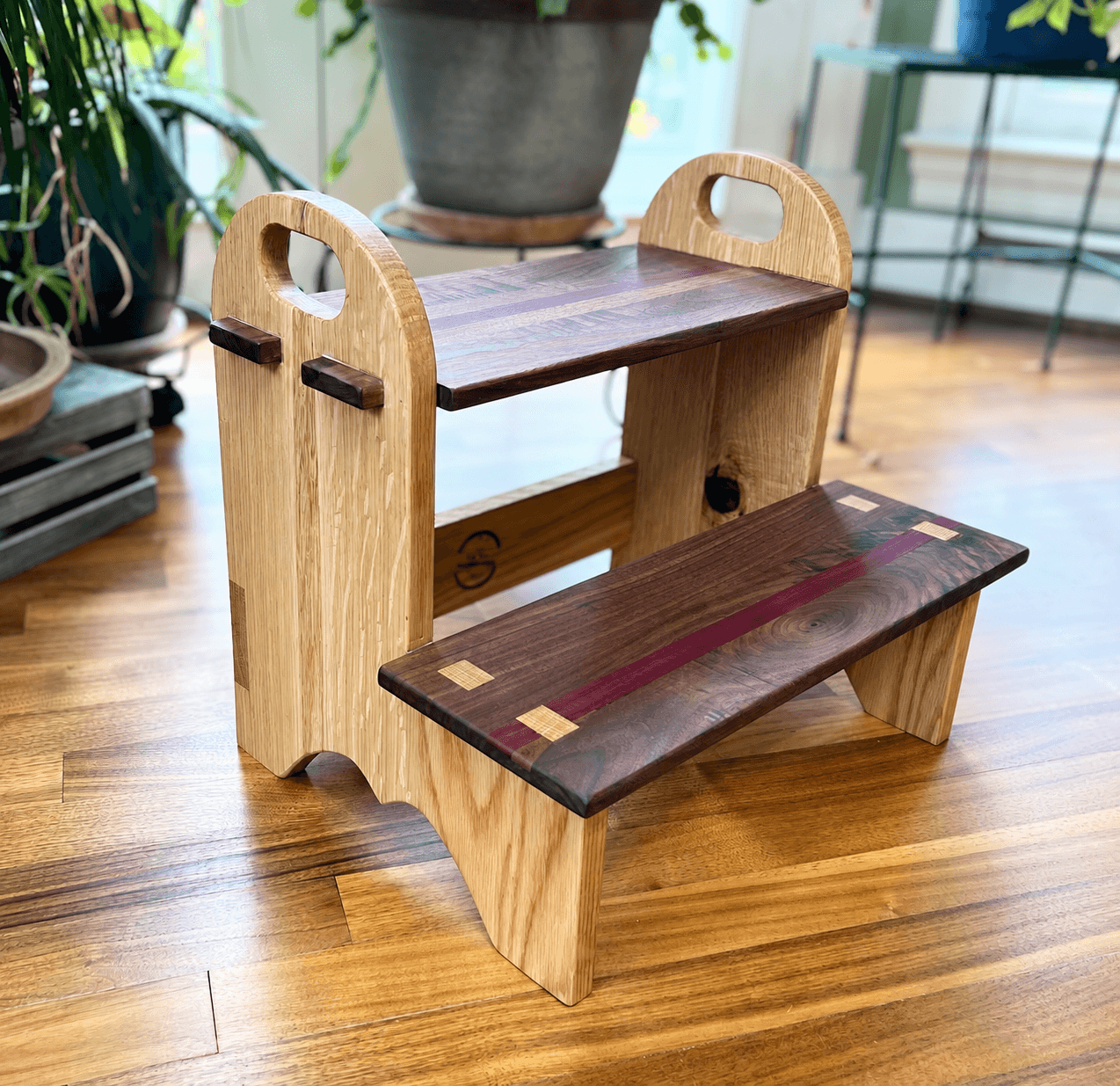 Two-step wooden stool with contrasting wood details and rounded carrying handles