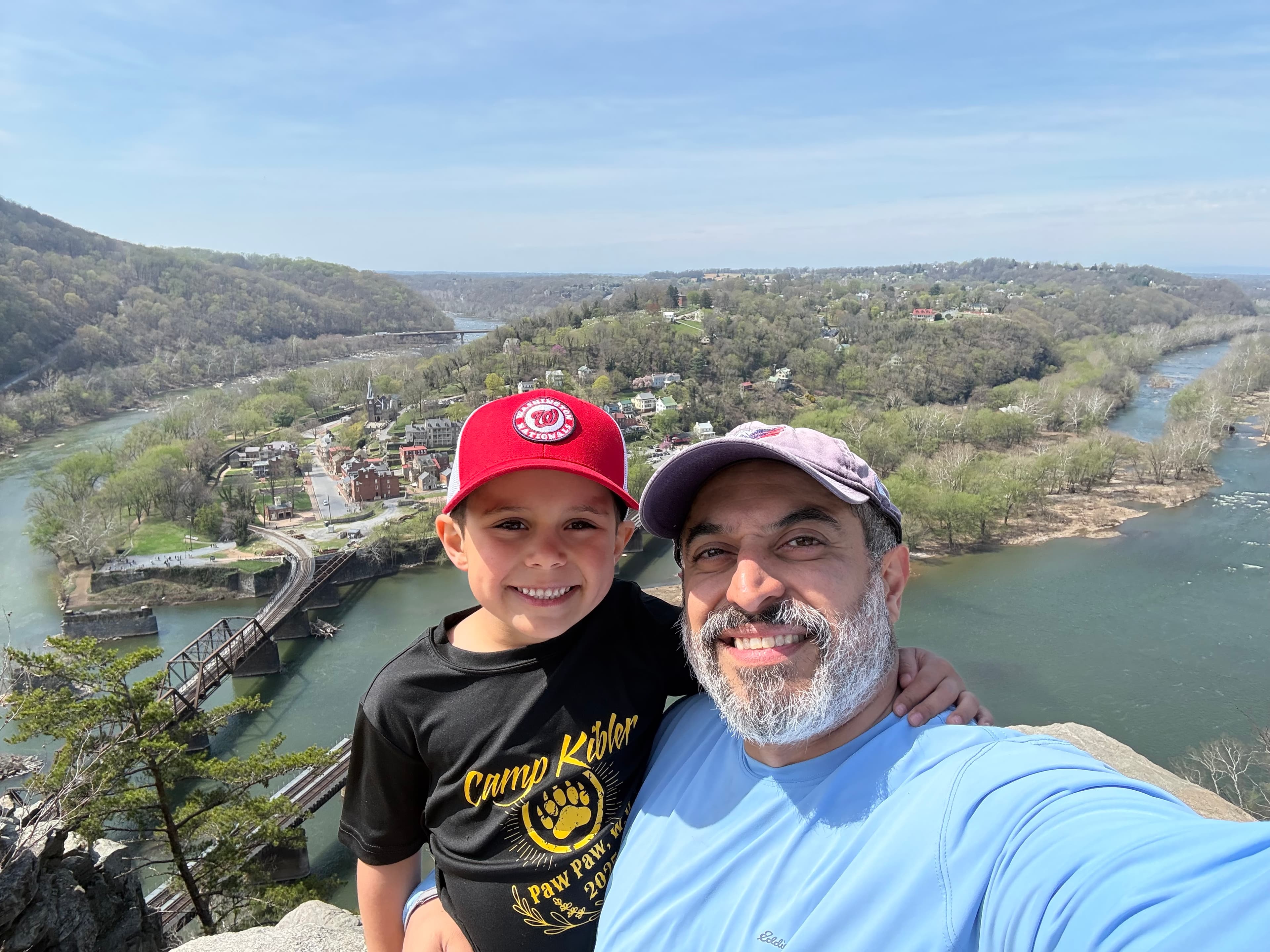 Ali G. with a child, overlooking a river and wooded hills